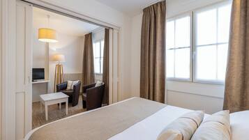 A hotel room with a bed, a desk with a chair, a television, and a lamp.