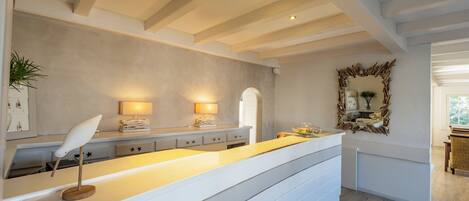 A modern kitchen with a central island, pendant lighting, and a rustic mirror.