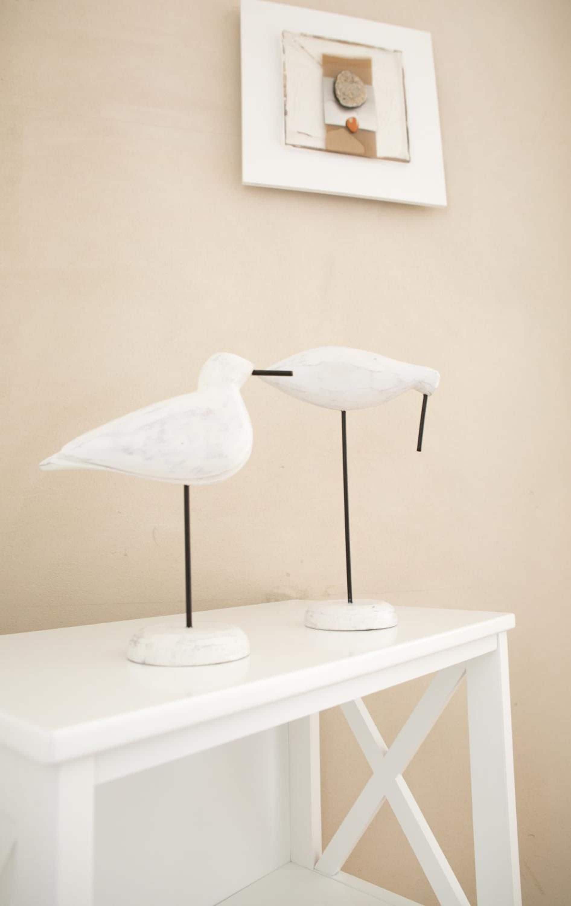 Un tavolo bianco con due lampade a forma di uccello bianche.