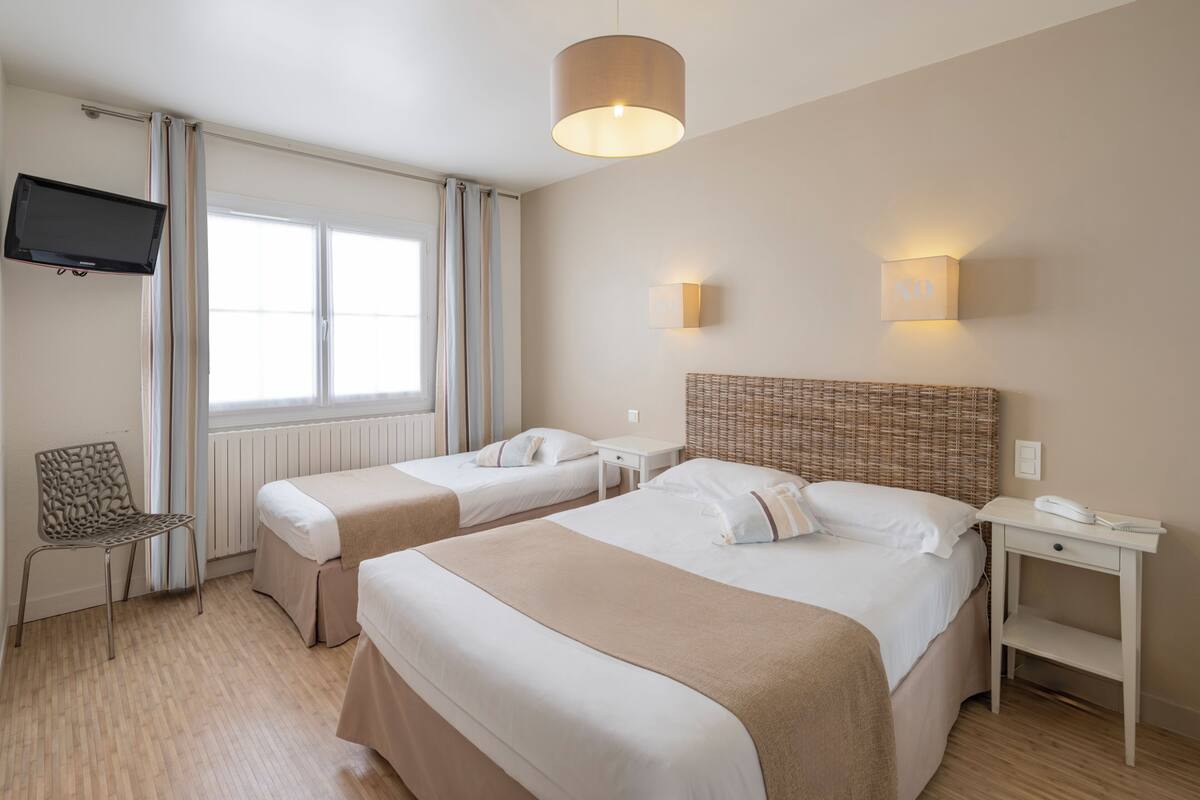 A hotel room with two beds, a TV, a desk, and a chair.