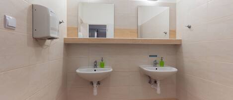 A restroom with two sinks, a hand dryer, and a mirror above each sink.