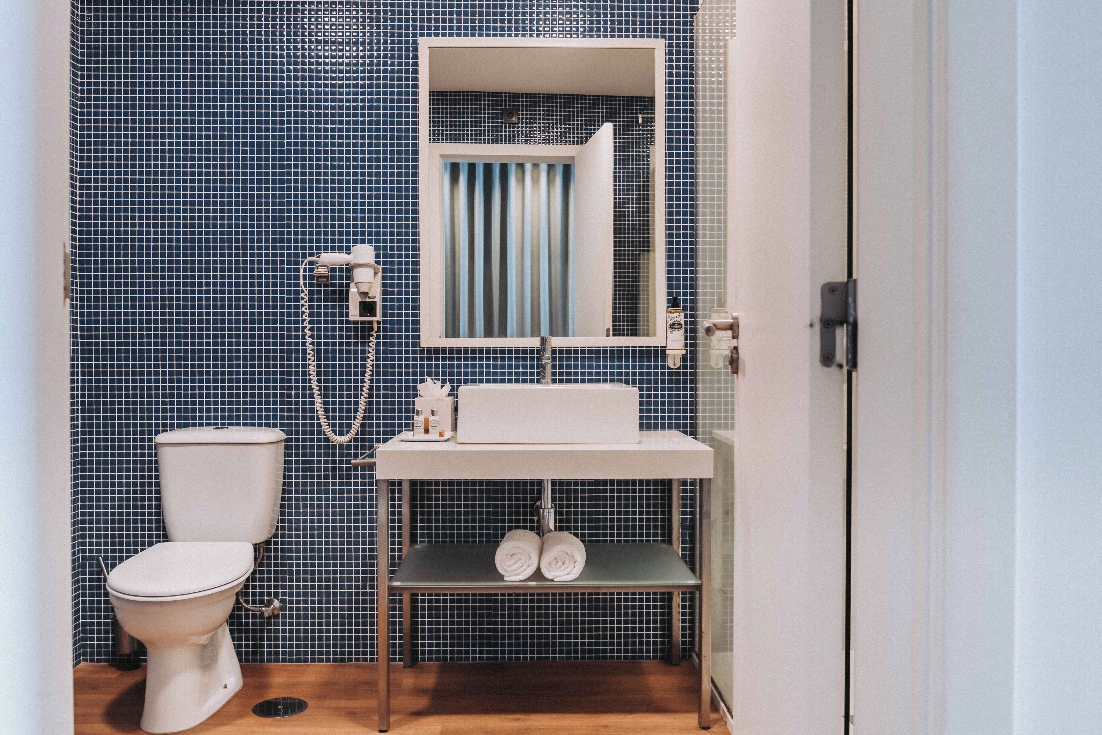 A bathroom with a toilet, sink, and mirror.