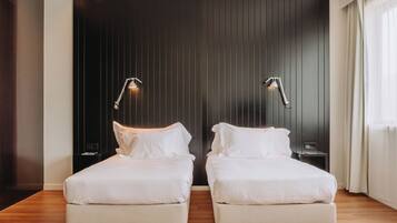 Una habitación de hotel moderna con dos camas individuales, paneles de madera oscura en las paredes y lámparas de noche.