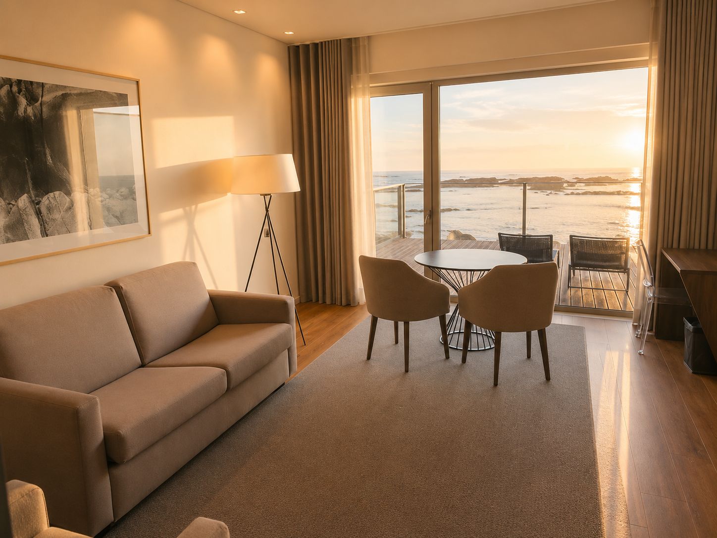 Une chambre d’hôtel avec un canapé, une table avec des chaises, une lampe sur pied et une grande fenêtre donnant sur la mer.