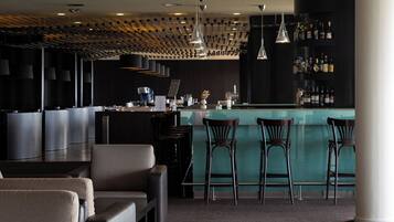 A modern bar area with a bar counter, multiple stools, and a seating area with sofas.