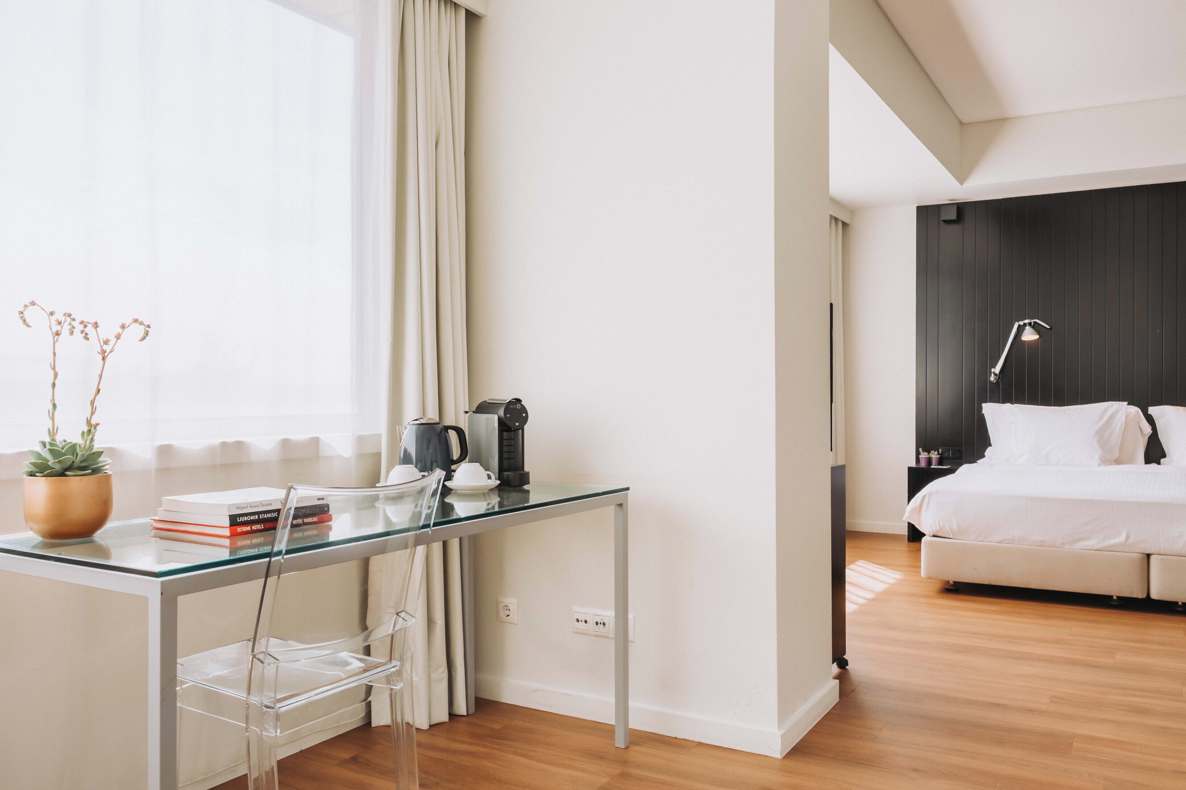 Une chambre d’hôtel moderne avec un bureau en verre, un lit et un mur en bois foncé.