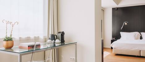 Une chambre d’hôtel moderne avec un bureau en verre, un lit et un mur en bois foncé.