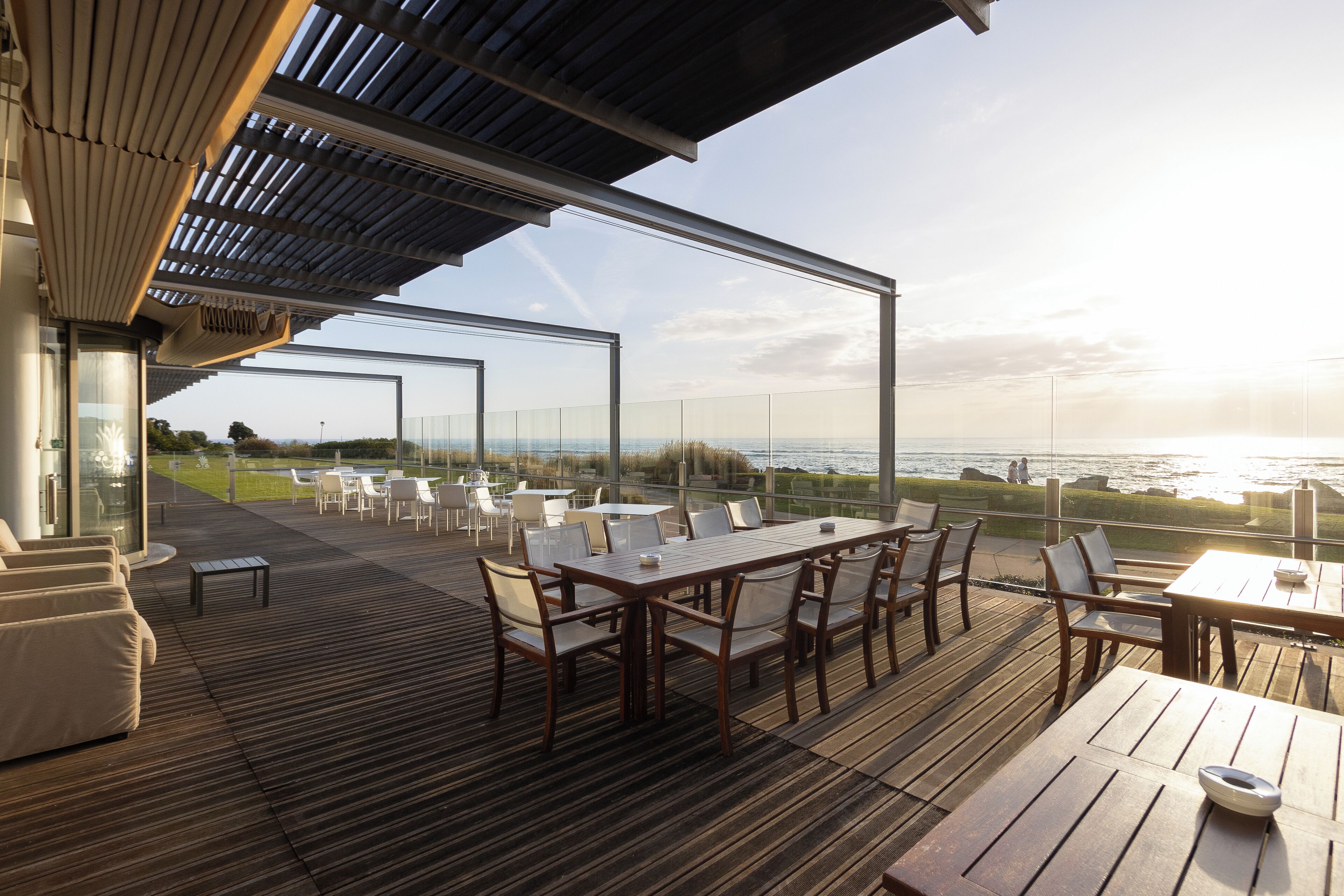 An outdoor deck with a wooden table and chairs, overlooking a body of water.