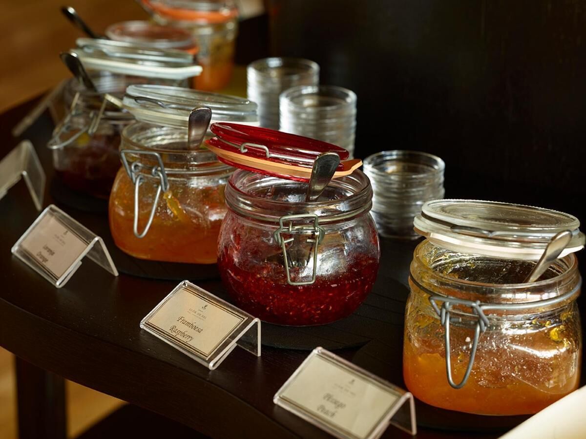 A buffet table with various jars of preserves and sauces, each labeled with their contents.