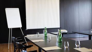 A conference room with a long table, chairs, a projector screen, and a whiteboard.
