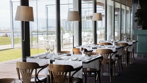 Een restaurant met gedekte tafels, grote ramen en uitzicht op het omliggende landschap.