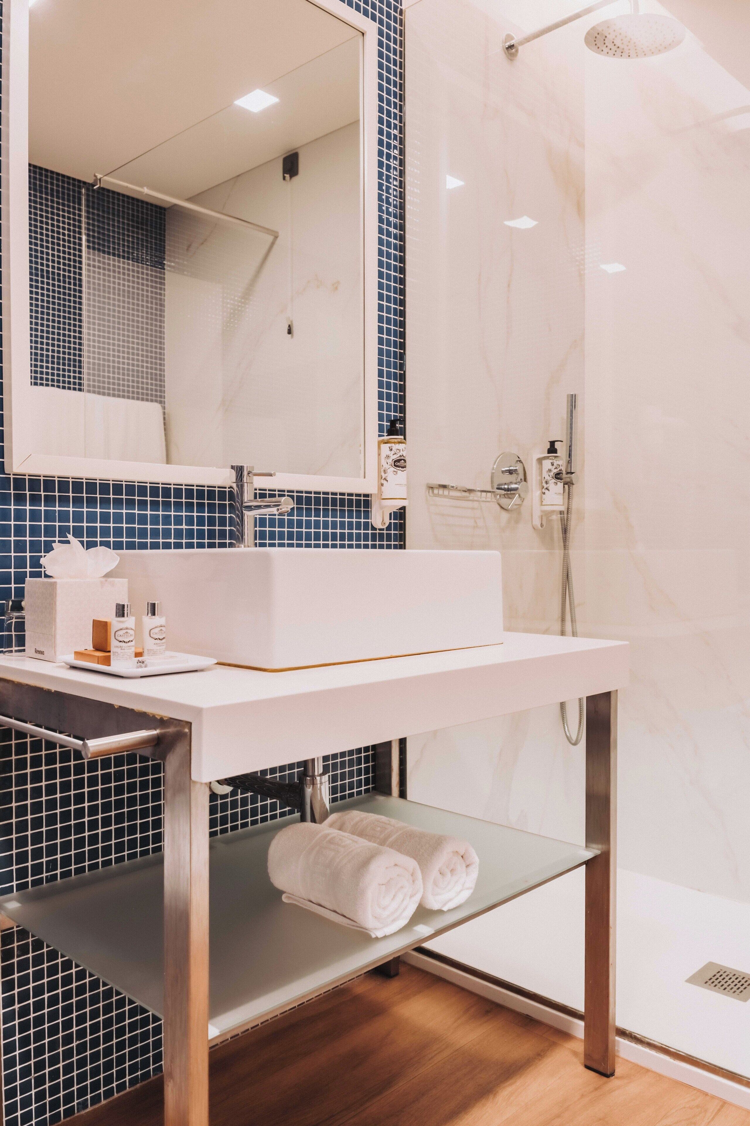 Un baño moderno con lavamanos, espejo y ducha blancos.