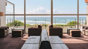 A room with a view of the ocean, featuring a large window, a sofa, and a small table.