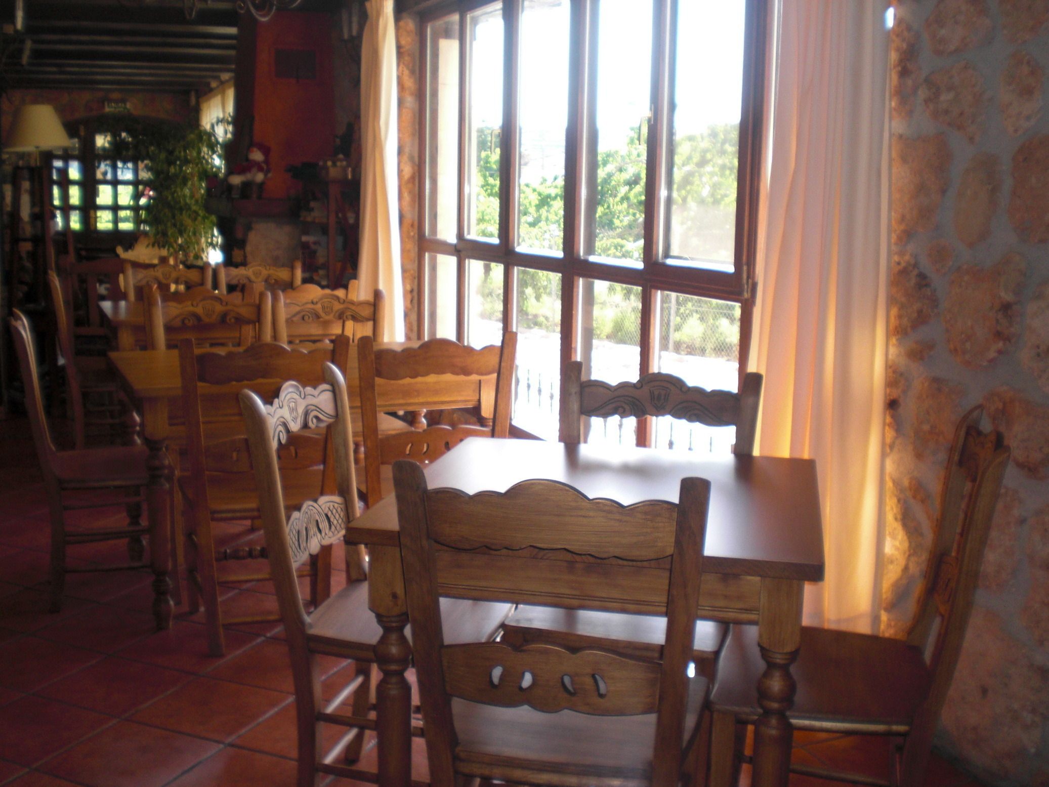 Un comedor con mobiliario de madera y ventanas grandes.