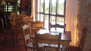 Un comedor con mobiliario de madera y ventanas grandes.