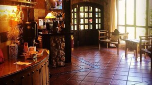 Un área de bar rústica con estanterías de madera, una barra de piedra y piso de baldosas.