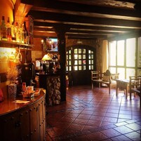 A rustic bar area with wooden shelves, a stone counter, and a tiled floor.