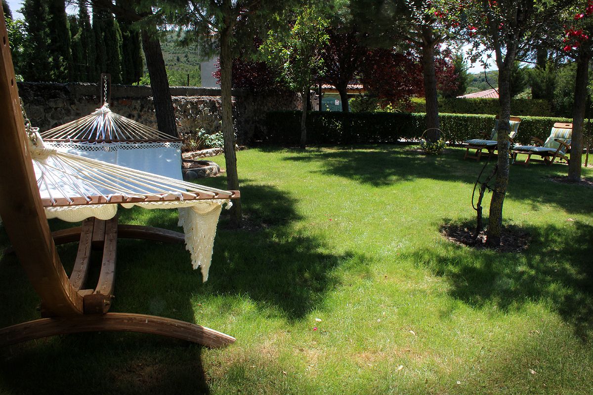 A hammock chair with a white canopy, a wooden swing, and a small table with a white cloth.