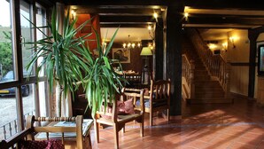 Un interior acogedor con muebles de madera, una planta grande y una escalera que sube.