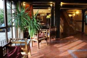 A cozy interior with wooden furniture, a large plant, and a staircase leading upstairs.