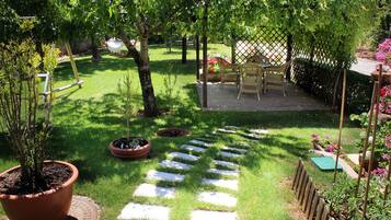 Un jardín con terraza de madera, plantas en macetas y una zona de estar.