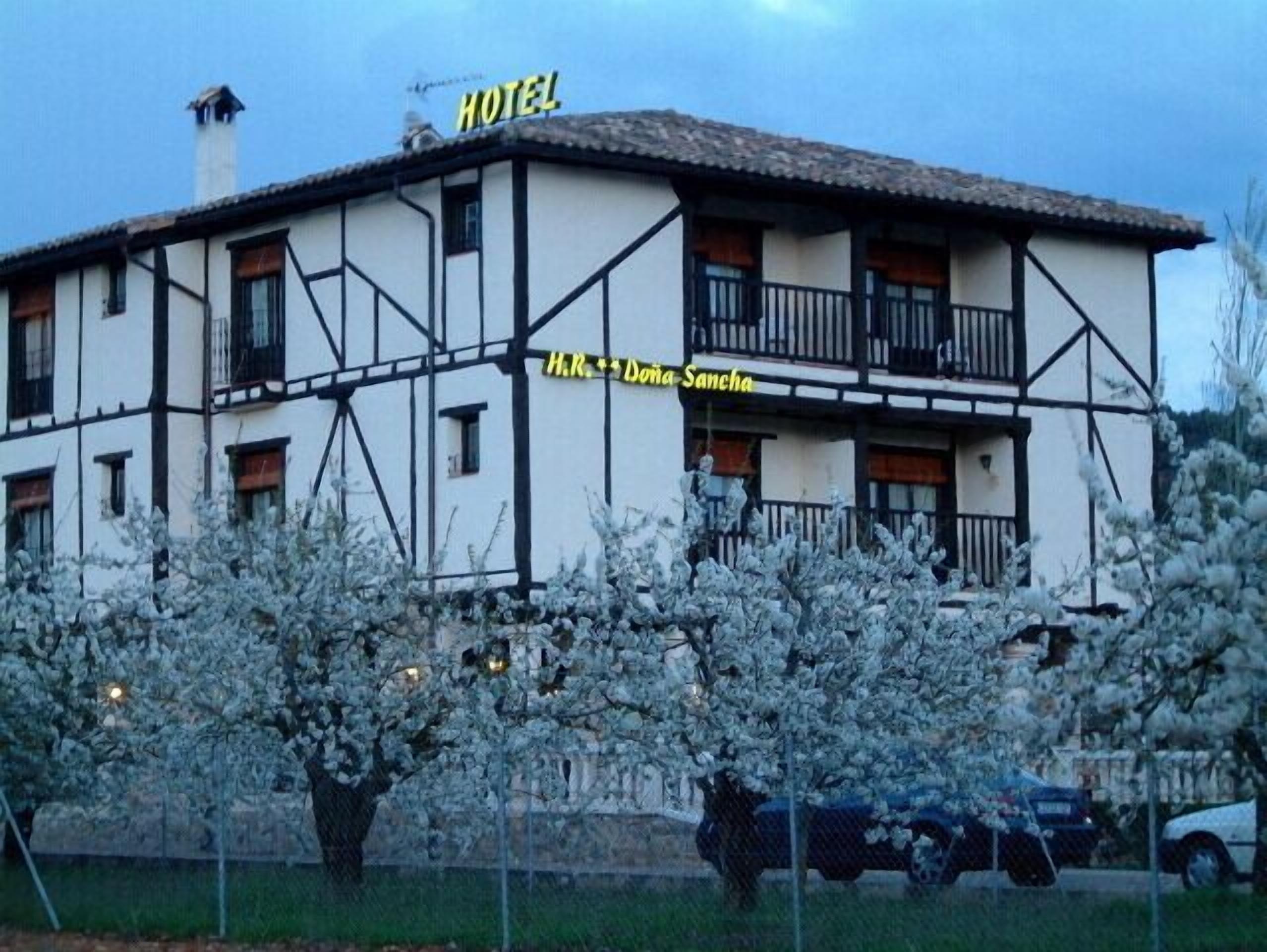 Un edificio de dos plantas con un cartel que dice "HOTEL" y "H.R. Dona Sancha".