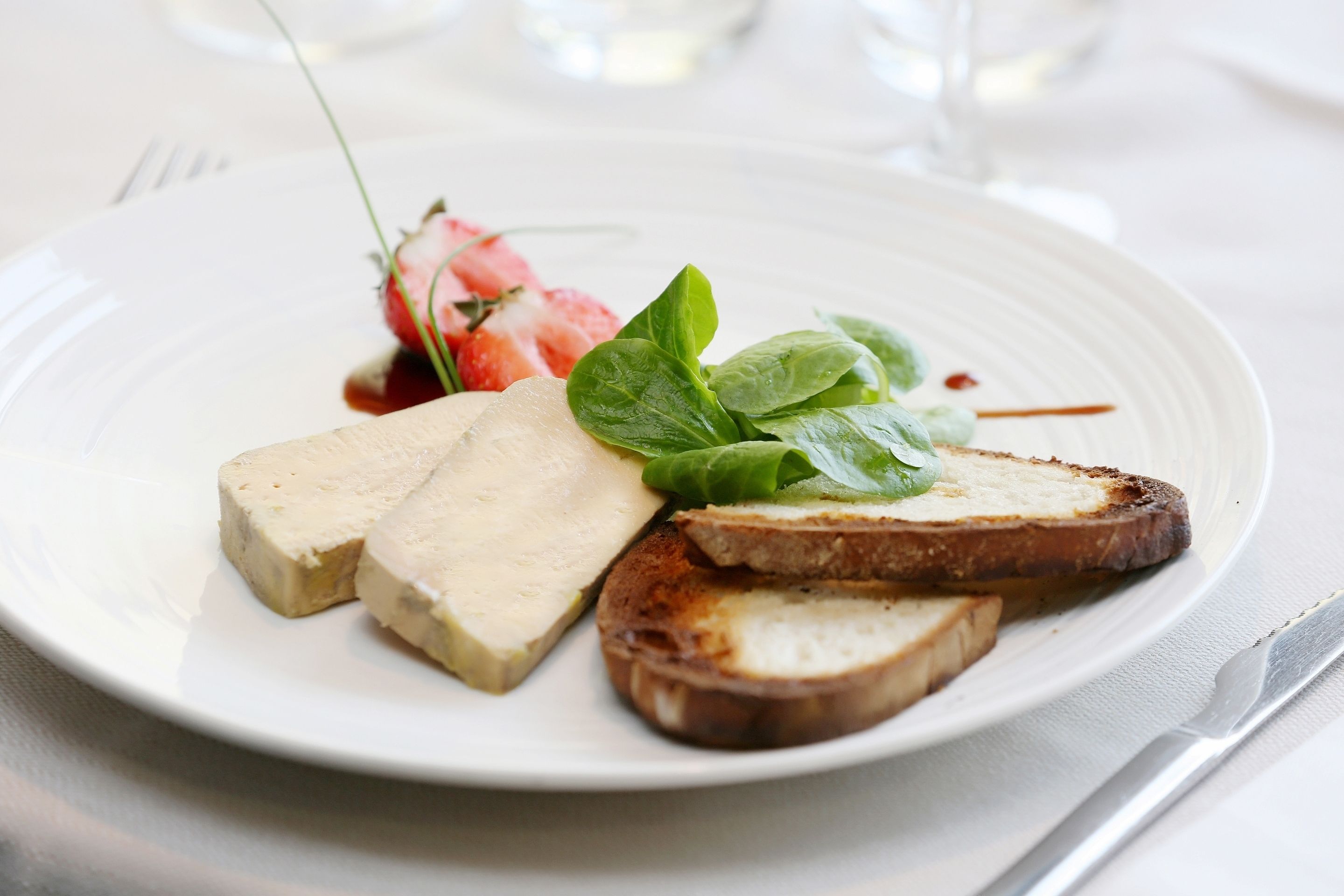 Ein Teller mit Brotscheiben, einem Stück Tofu und einer Erdbeere.