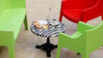 A small round table with a striped tablecloth, a menu, a glass of water, and a cup of coffee.