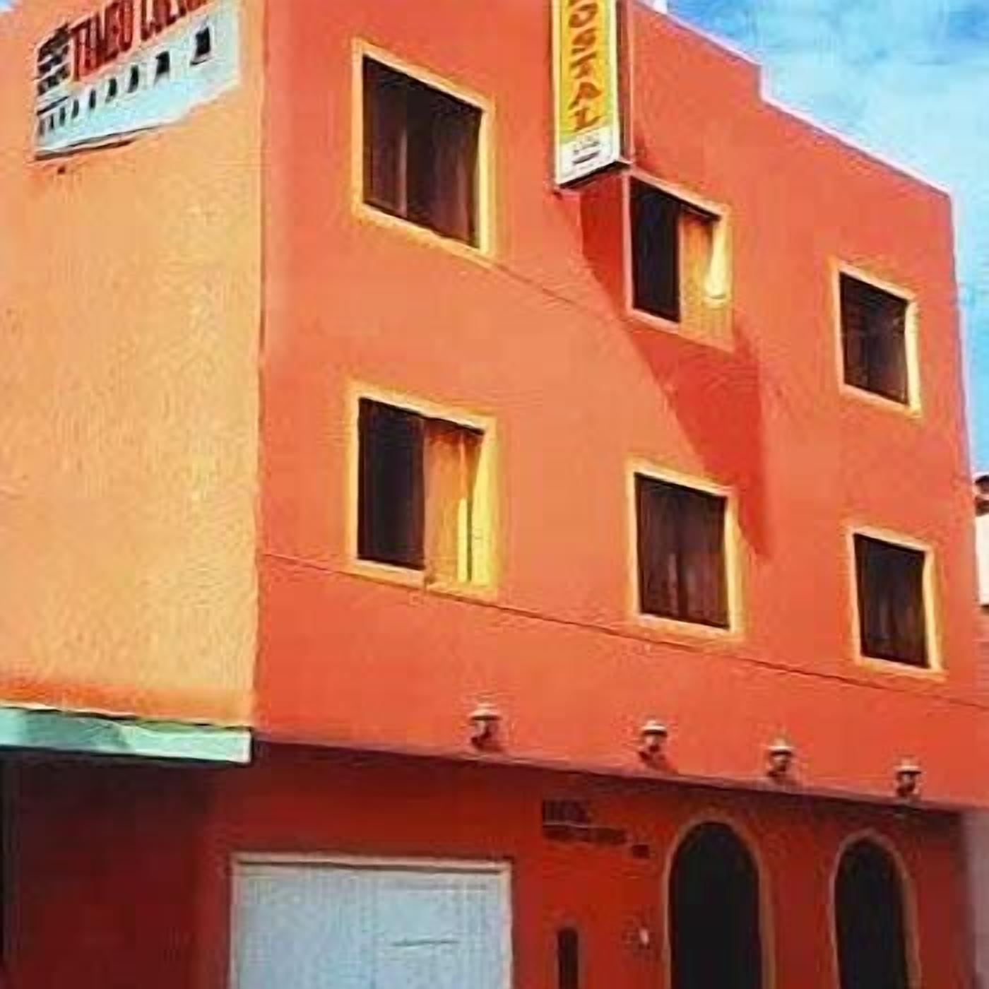 Un edificio de varios pisos con fachada roja, numerosas ventanas y un garaje visible.