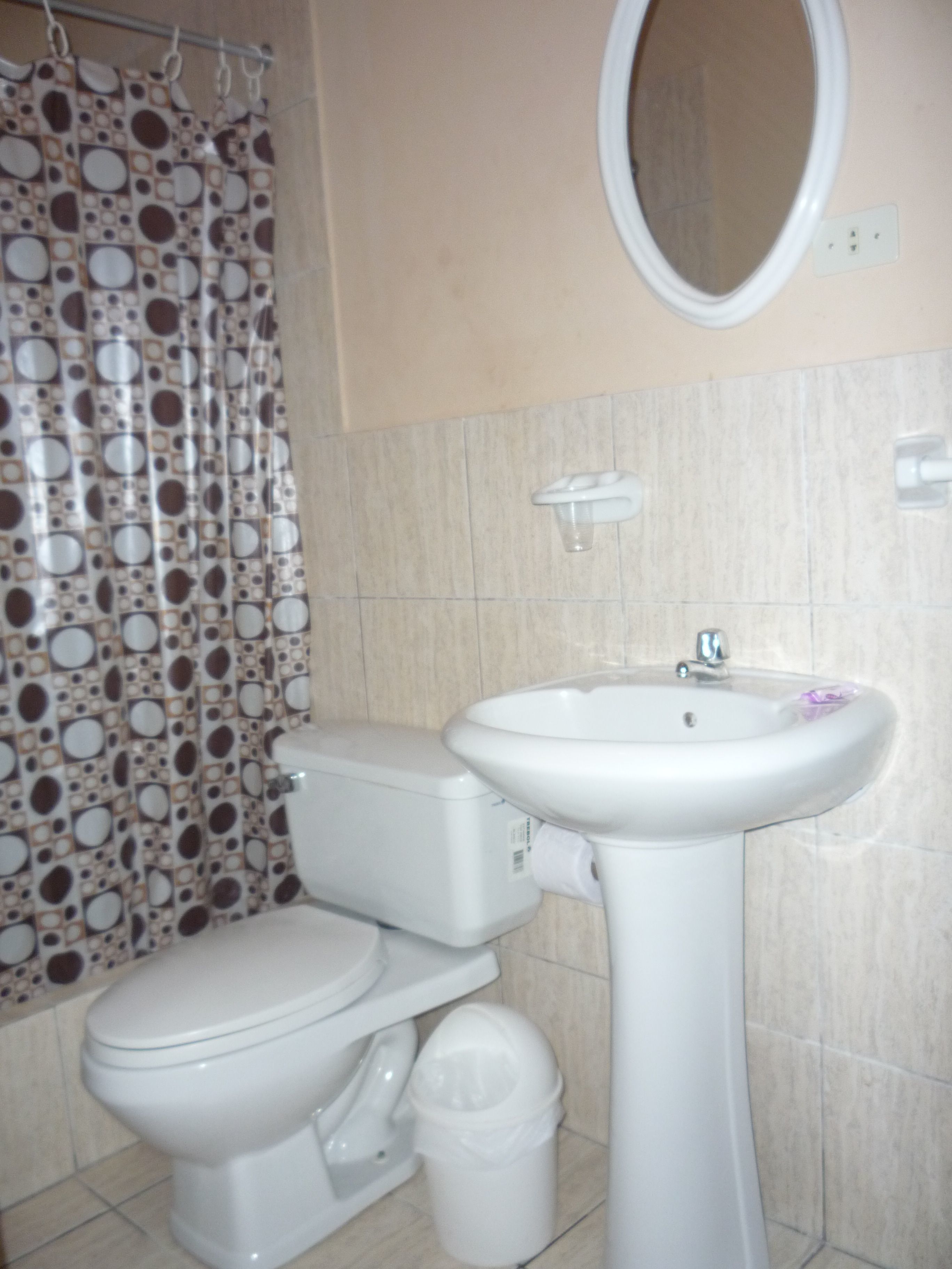 Un baño con inodoro, lavamanos y cortina de ducha.