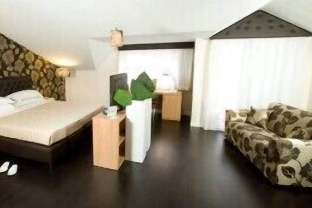 Une chambre à coucher avec un lit, un canapé, une petite table et une plante en pot.