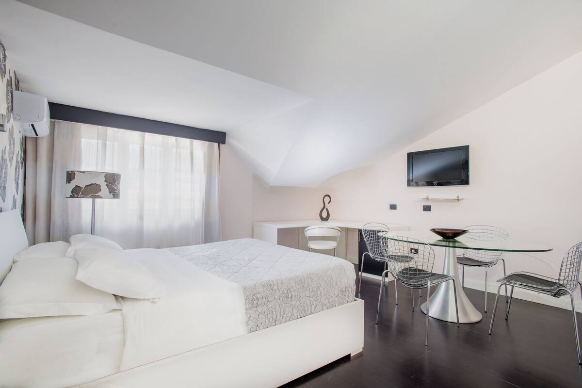Une chambre à coucher moderne avec un lit, un bureau et un téléviseur.