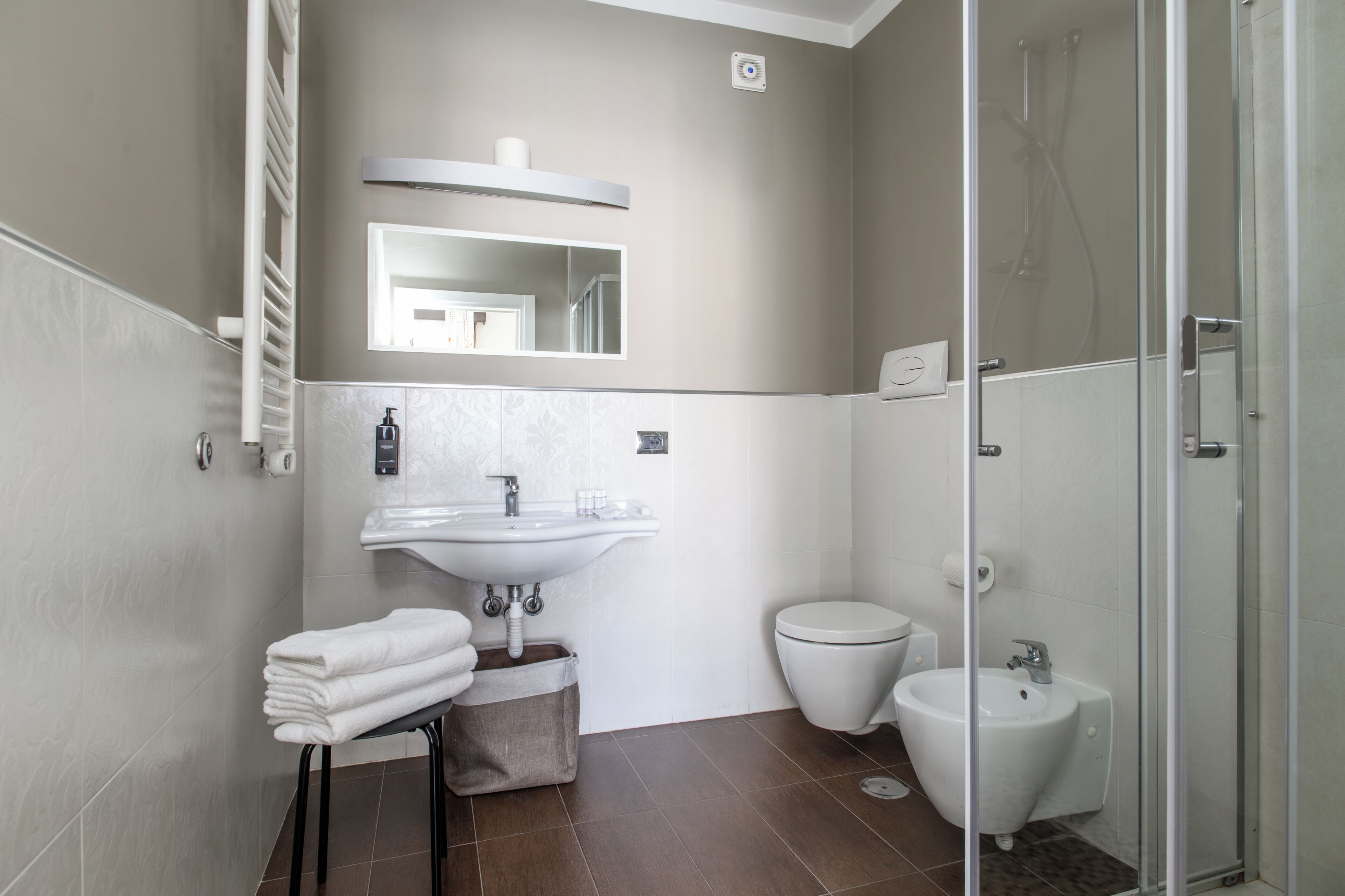 Un baño moderno con lavamanos, inodoro, bidé y cabina de ducha de vidrio.