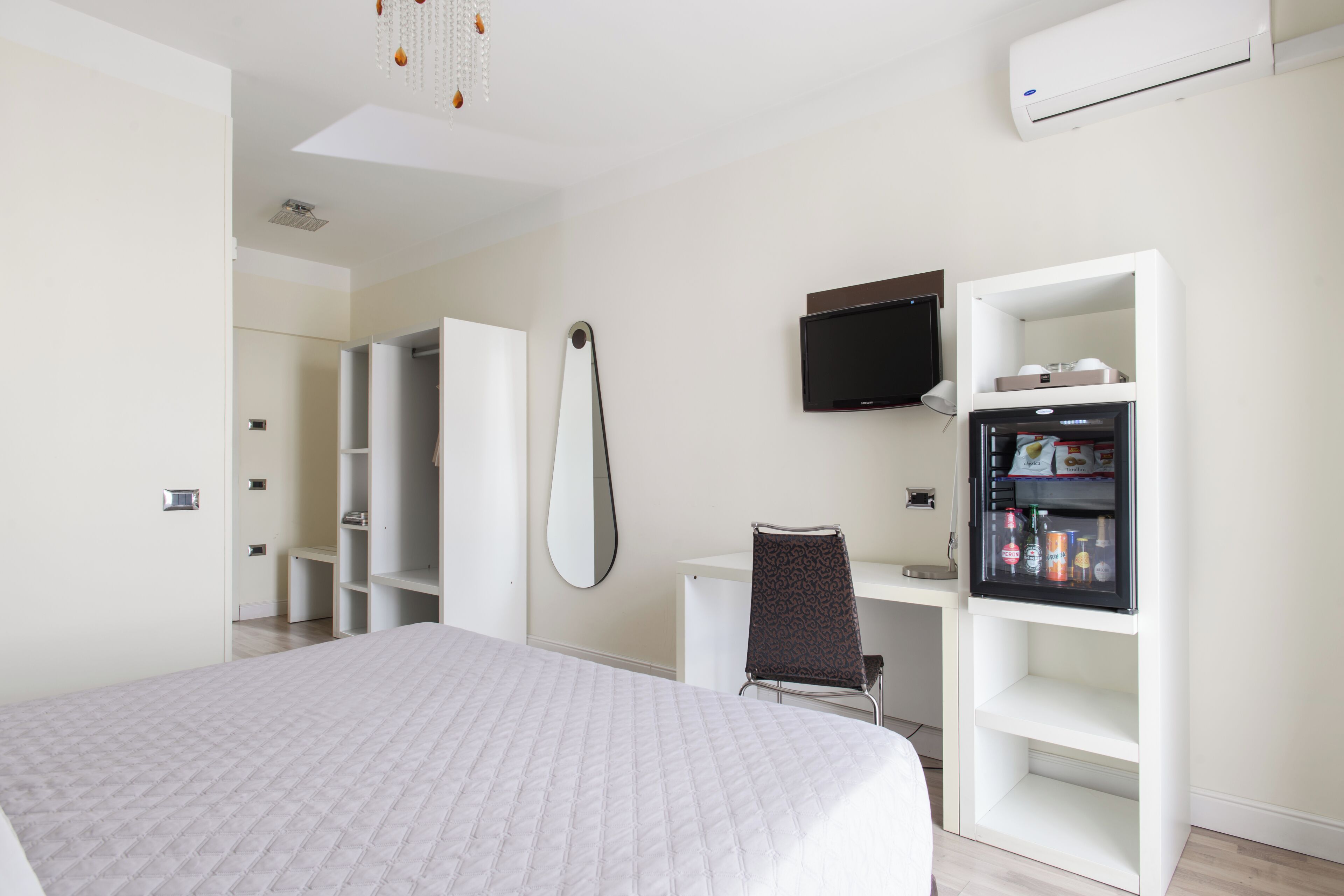 Una habitación de hotel con cama, escritorio, silla, televisor y minibar.