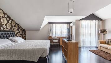 Een slaapkamer met een bed, bureau, televisie en een bank.