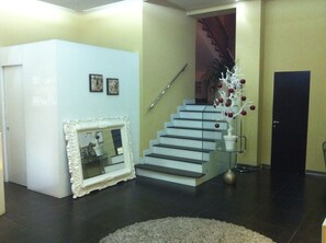 Una escalera con barandilla blanca, un espejo con marco blanco y una planta decorativa con bayas rojas.