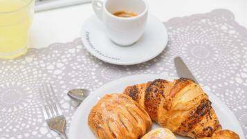 Una colazione con croissant, una tazza di caffè e una ciotola di cereali su un tavolo con una tovaglia all'uncinetto.