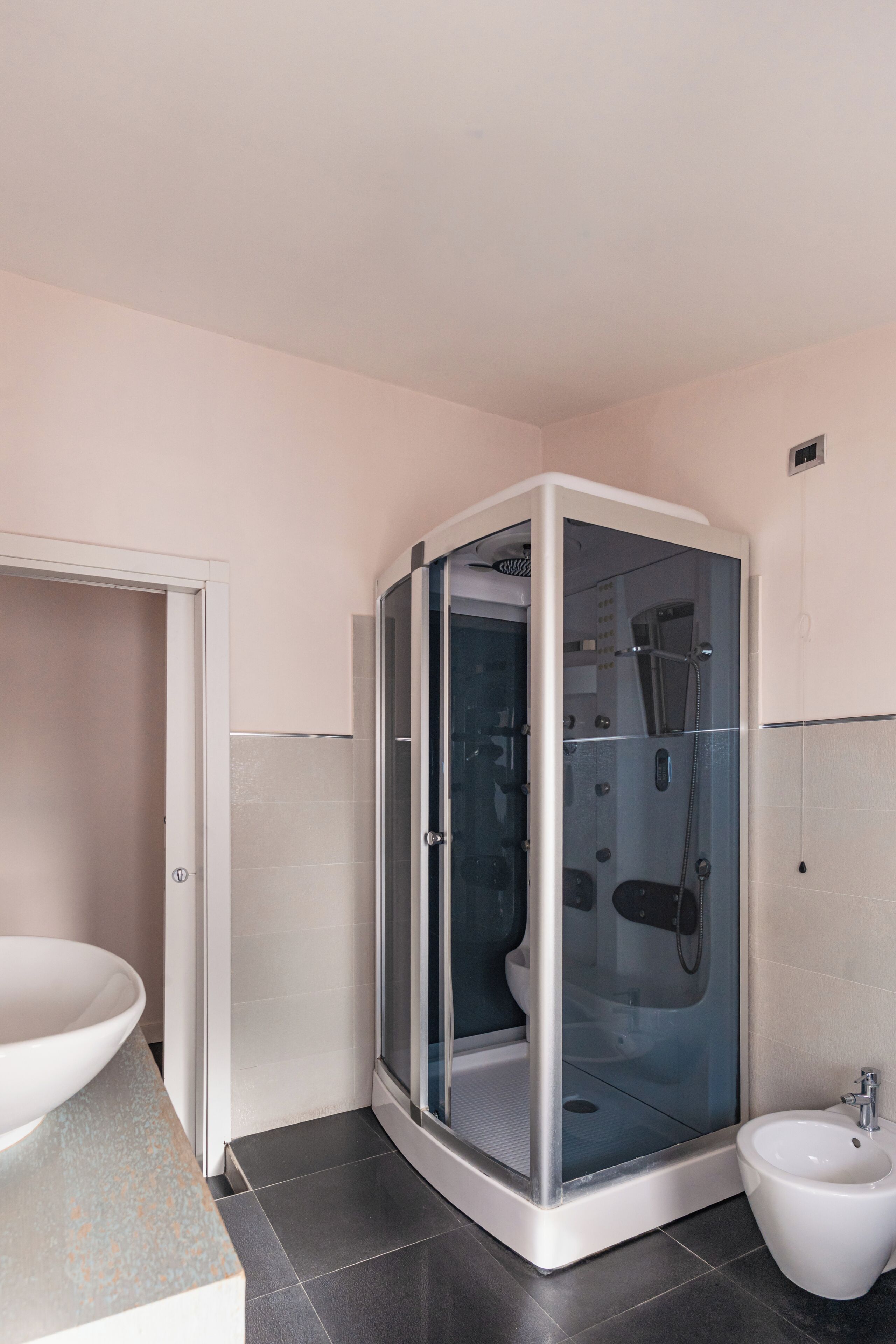 A modern bathroom with a glass-enclosed shower, a sink, and a bidet.