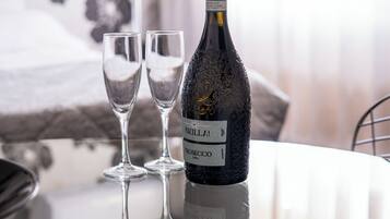 Una bottiglia di vino BRILLAI e due bicchieri su una superficie riflettente in una stanza con carta da parati a motivi floreali.