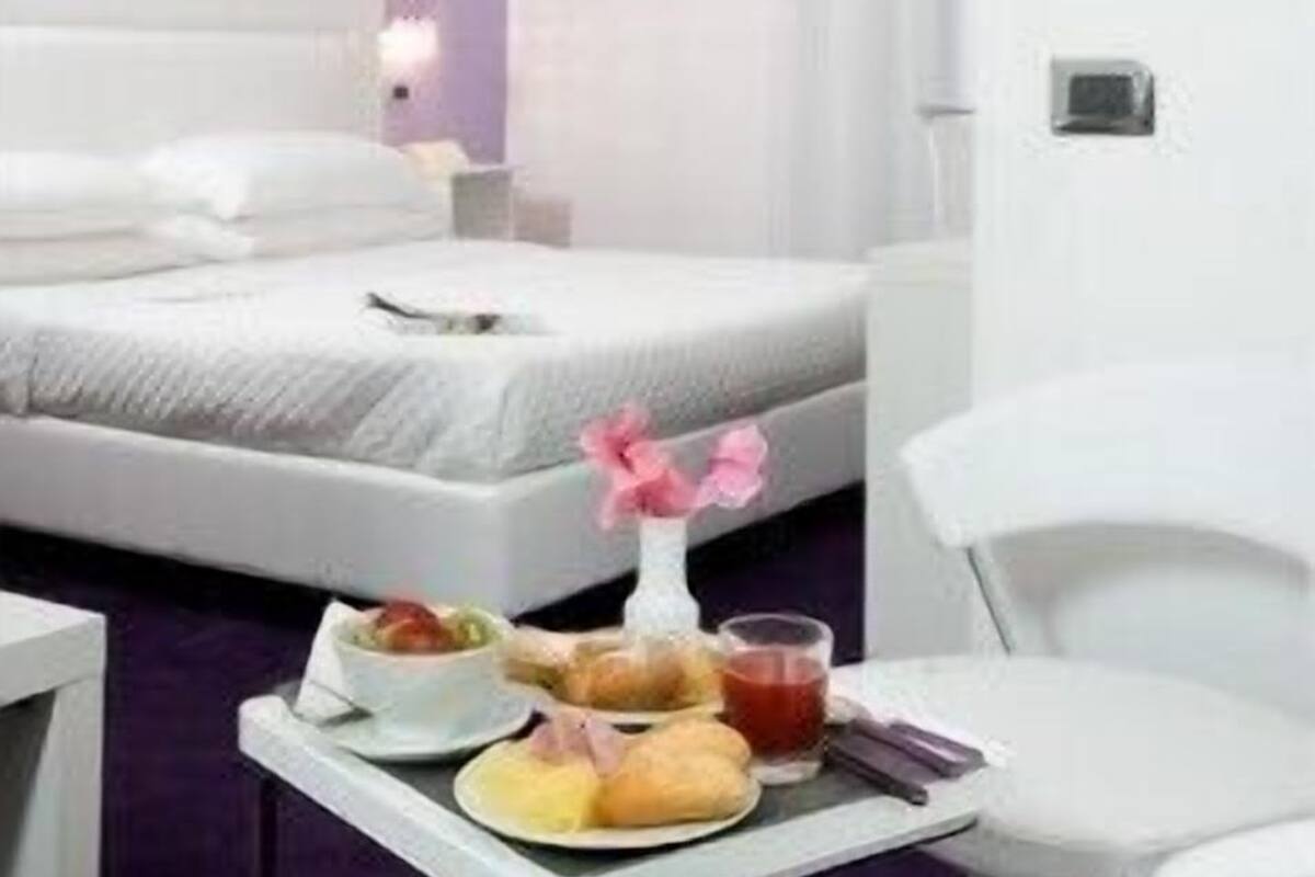 Une chambre d’hôtel avec un lit, une table de chevet, une chaise et un plateau contenant des articles pour le petit-déjeuner.