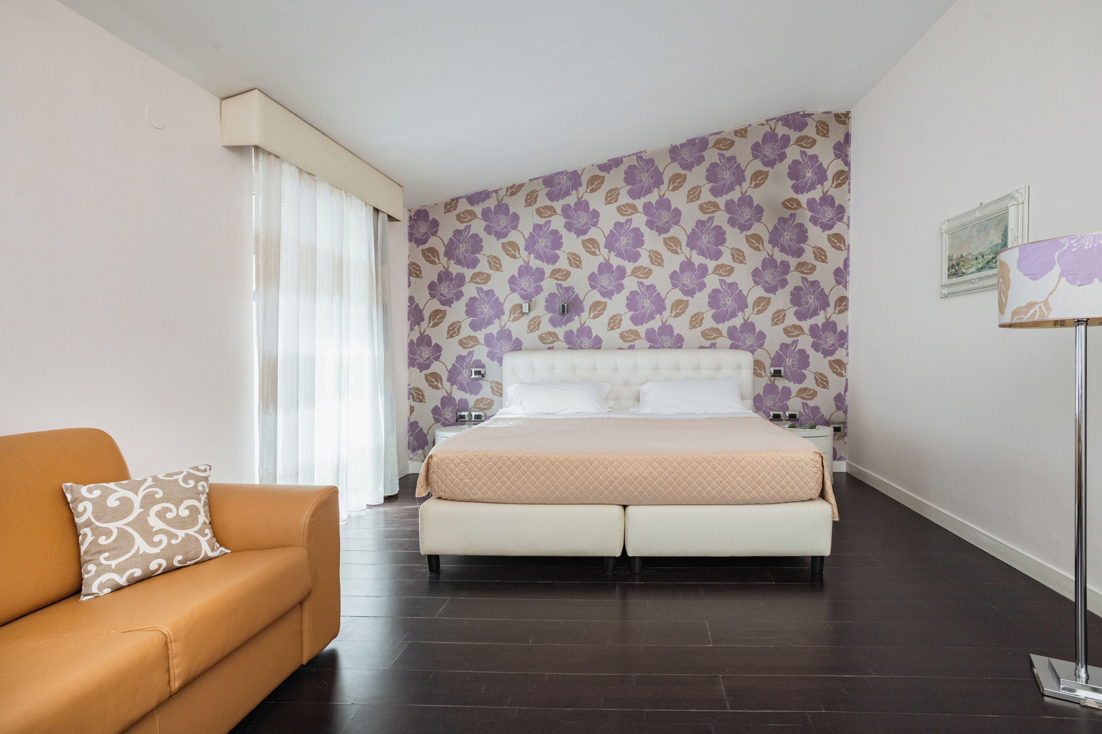 Une chambre à coucher avec un lit, un canapé, une table de chevet et une lampe.