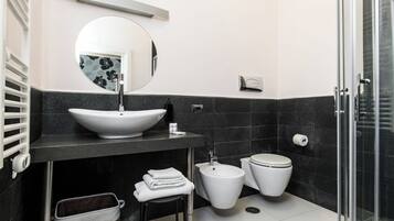 Un baño moderno con un lavamanos grande, inodoro, bidé y cabina de ducha de vidrio.