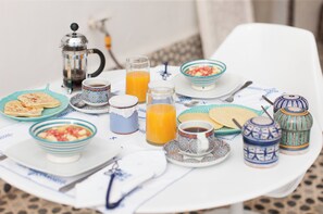 A breakfast table with various dishes, including a coffee pot, orange juice, and bowls of food.