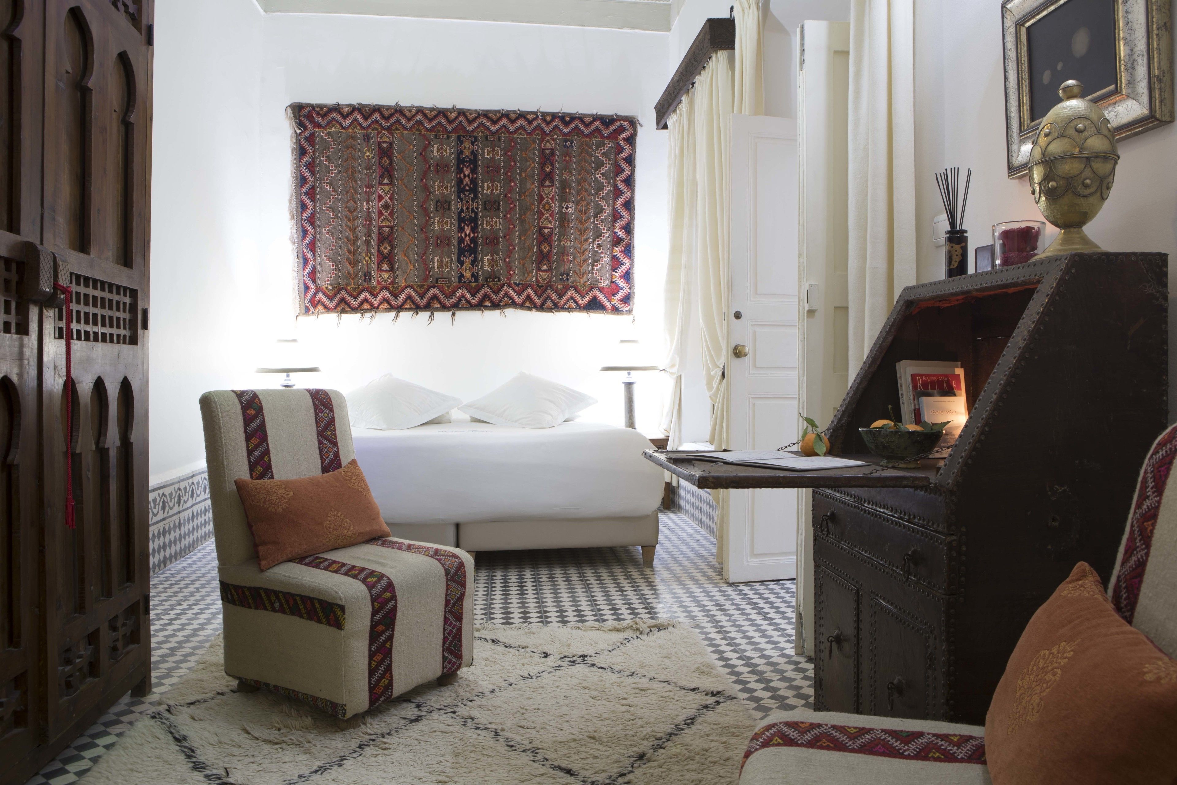Une chambre à coucher avec un lit, une chaise, un bureau et un tapis à motifs.