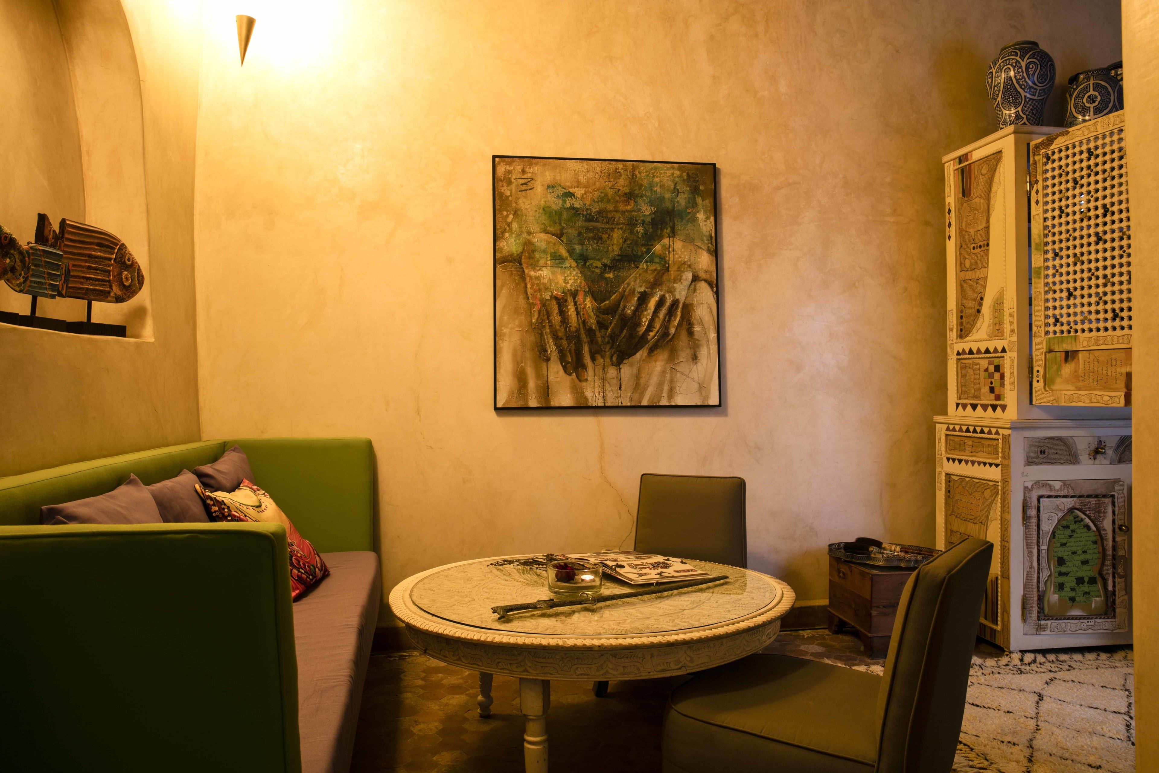 A cozy room with a round table, a green sofa, and a decorative cabinet.