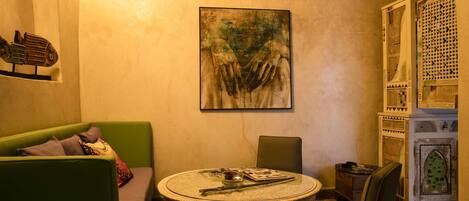 A cozy room with a round table, a green sofa, and a decorative cabinet.