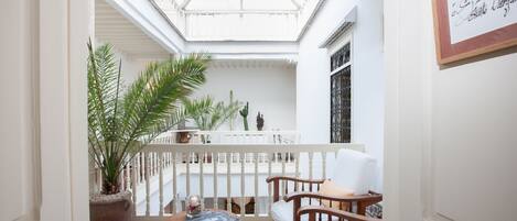 A cozy balcony with a checkered floor, wooden furniture, and potted plants.