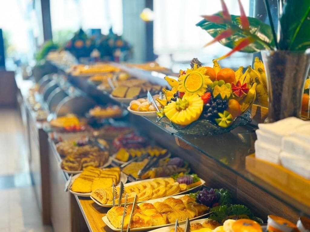 A buffet with various food items including fruits, pastries, and sandwiches.