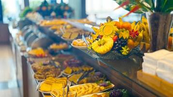 A buffet with various food items including fruits, pastries, and sandwiches.