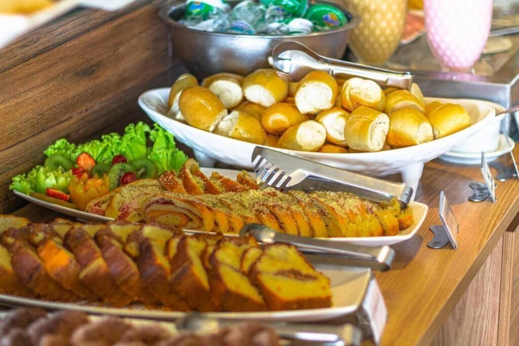 Una mesa de buffet con diversos platos, incluyendo un pastel enrollado, un recipiente con verduras en rodajas y un bol de pastas redondas.